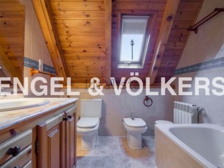 Charming attic bathroom with wooden beams, skylight, and modern fixtures.