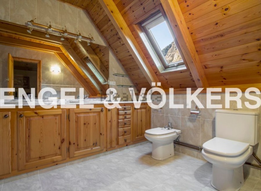 This stunning bathroom boasts a unique wooden beamed ceiling and skylights, creating a bright and airy atmosphere.
