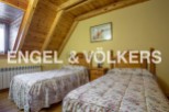 Charming attic bedroom with twin beds, featuring a wooden beamed ceiling and floral bedding.