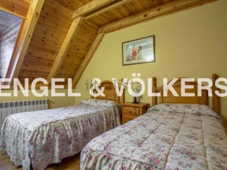 Charming attic bedroom with twin beds, featuring a wooden beamed ceiling and floral bedding.