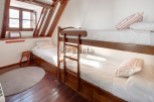 Cozy attic bedroom with wooden bunk beds and a single bed, perfect for a family getaway.