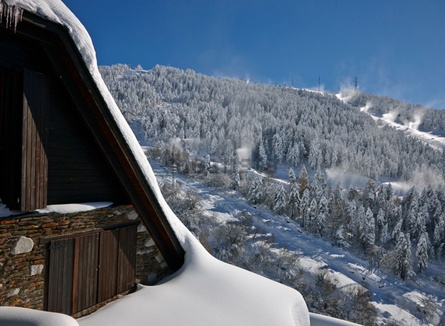 This stunning chalet boasts a picturesque snow-covered roof and rustic stone and wood exterior.