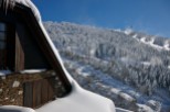This stunning chalet boasts a picturesque snow-covered roof and rustic stone and wood exterior.
