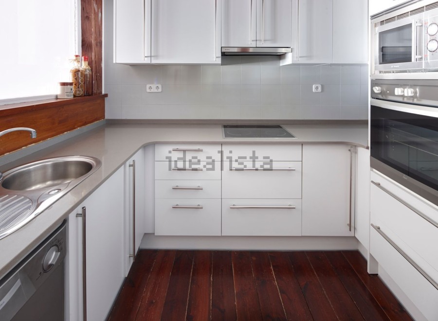 Modern kitchen with white cabinets and grey countertops.