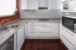 Modern kitchen with white cabinets and grey countertops.