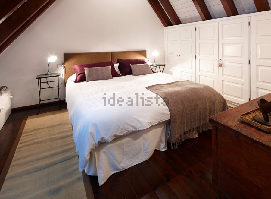 Cozy attic bedroom with wooden beams and built-in wardrobes.