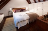 Cozy attic bedroom with wooden beams and built-in wardrobes.
