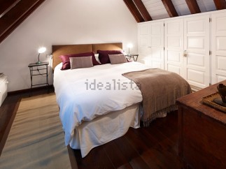 Cozy attic bedroom with wooden beams and built-in wardrobes.
