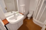 This charming bathroom boasts a modern sink and toilet, complemented by a clean white color scheme and wood accents.