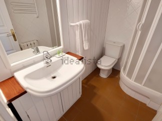 This charming bathroom boasts a modern sink and toilet, complemented by a clean white color scheme and wood accents.