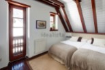 Charming attic bedroom with twin beds, exposed wooden beams, and a rustic wooden door leading to outdoor views.