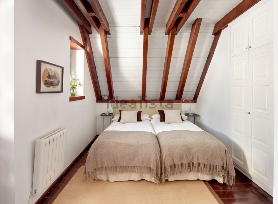 Charming attic bedroom with twin beds, exposed wooden beams, and built-in wardrobe.