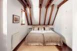 Charming attic bedroom with twin beds, exposed wooden beams, and built-in wardrobe.