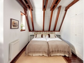 Charming attic bedroom with twin beds, exposed wooden beams, and built-in wardrobe.