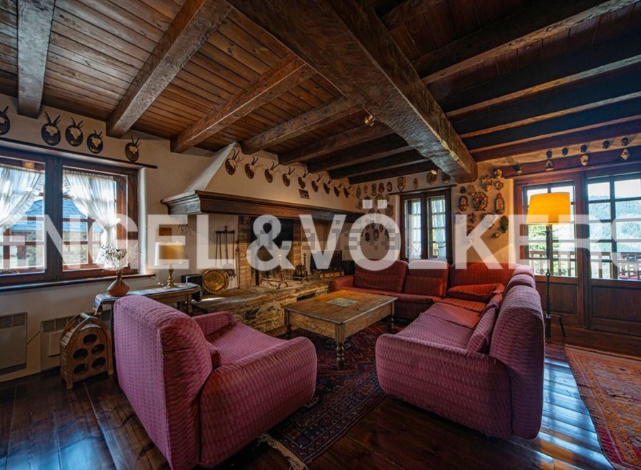 Rustic mountain home with exposed wooden beams, a large stone fireplace, and comfortable seating.