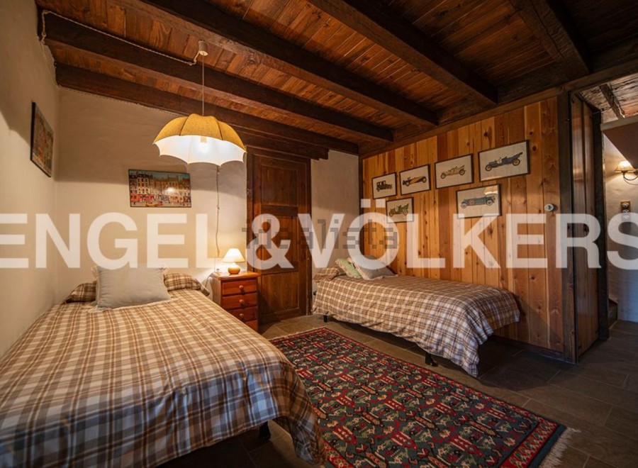 Charming rustic bedroom with twin beds, wooden beams, and vintage car artwork.