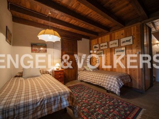 Charming rustic bedroom with twin beds, wooden beams, and vintage car artwork.
