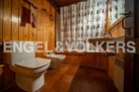 Rustic bathroom with wooden walls and tiled floor.