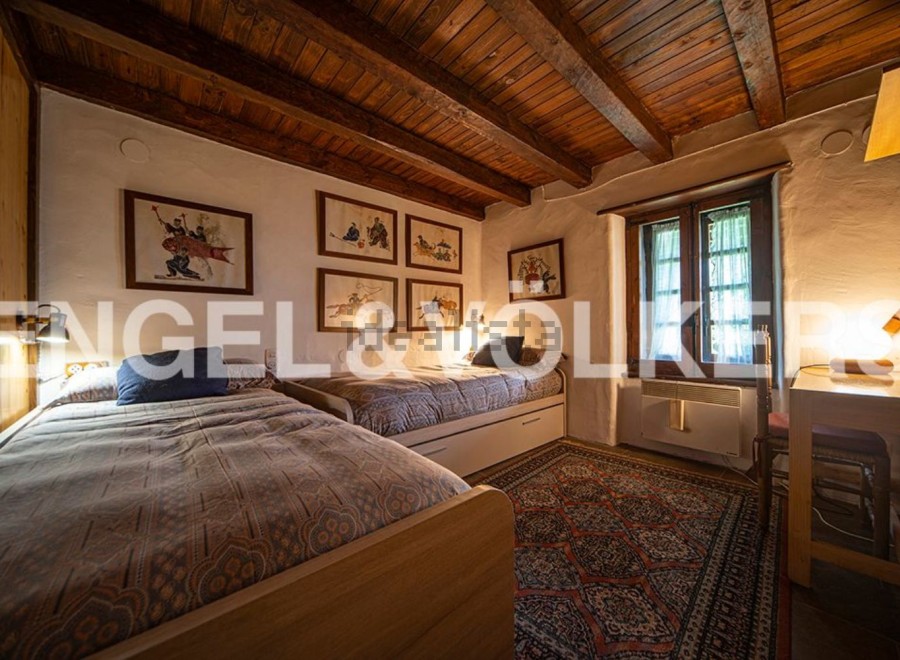Charming rustic bedroom with twin beds, wooden beams, and antique artwork.