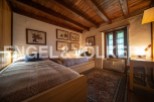 Charming rustic bedroom with twin beds, wooden beams, and antique artwork.