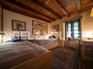 Charming rustic bedroom with twin beds, wooden beams, and antique artwork.