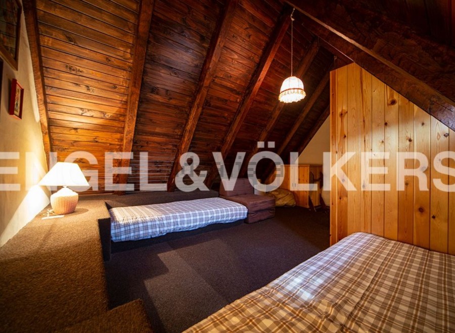 Cozy attic bedroom with wooden beams and built-in beds, perfect for a mountain getaway.