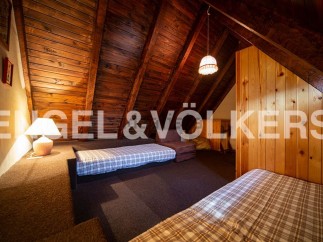 Cozy attic bedroom with wooden beams and built-in beds, perfect for a mountain getaway.