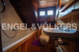 Charming attic bathroom with wooden features, including a bathtub, toilet, and sink.