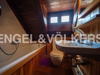 Charming attic bathroom with wooden features, including a bathtub, toilet, and sink.