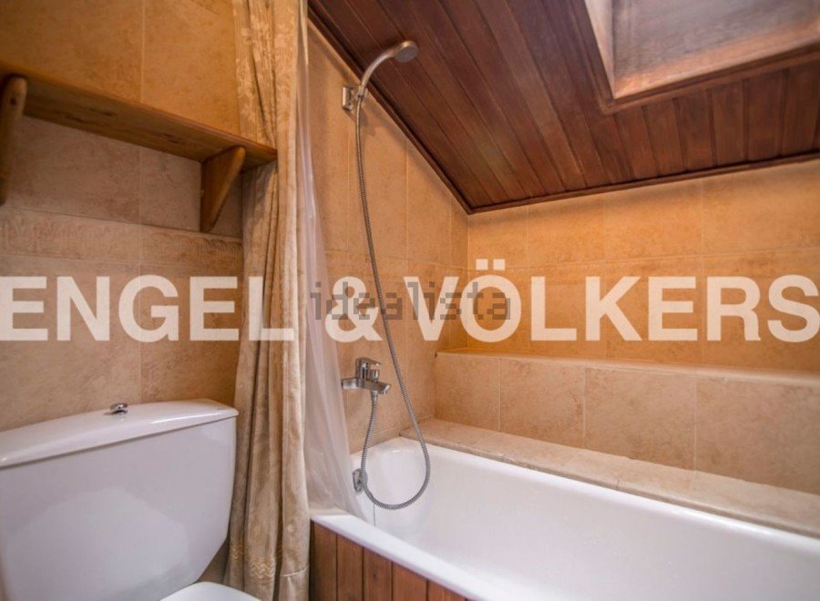 Charming attic bathroom with wooden accents and a built-in shelf.