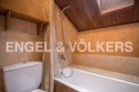 Charming attic bathroom with wooden accents and a built-in shelf.