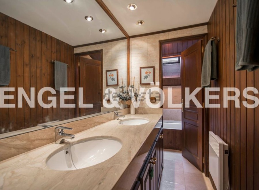 This luxurious bathroom boasts double sinks, marble countertops, and rich wood paneling.