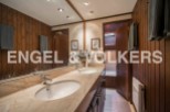 This luxurious bathroom boasts double sinks, marble countertops, and rich wood paneling.
