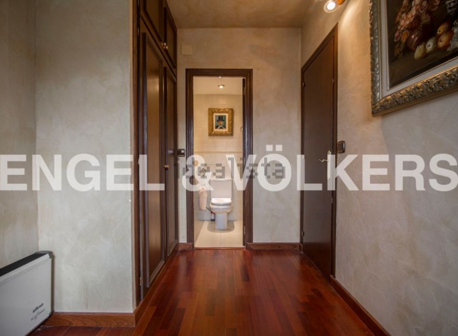 This stunning property boasts a spacious hallway with rich hardwood floors, leading to a well-appointed bathroom.