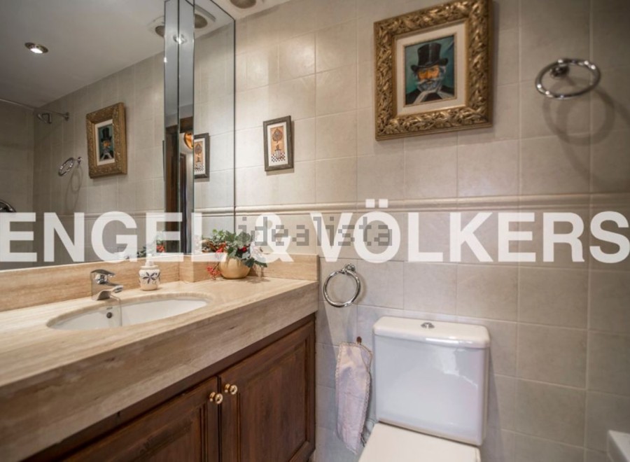 This luxurious bathroom boasts a spacious vanity with marble countertops and wooden cabinetry, complemented by elegant framed artwork.