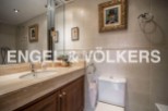 This luxurious bathroom boasts a spacious vanity with marble countertops and wooden cabinetry, complemented by elegant framed artwork.