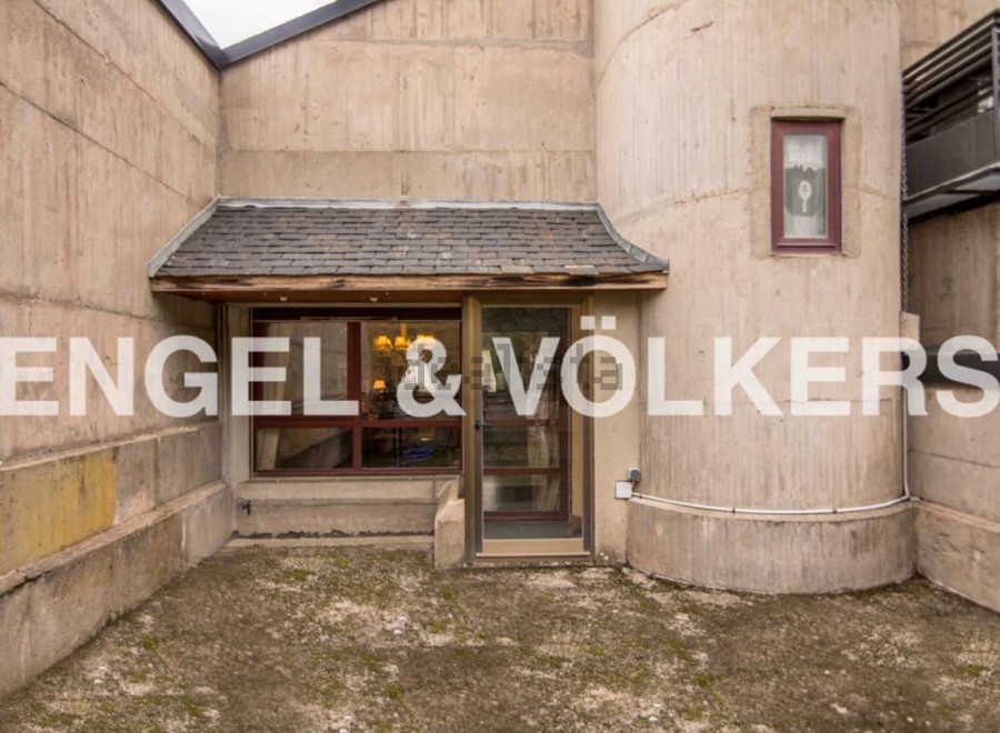 This unique property boasts a striking concrete exterior with a blend of modern and rustic design elements.