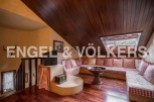Cozy attic room with L-shaped sofa and wood-burning stove.