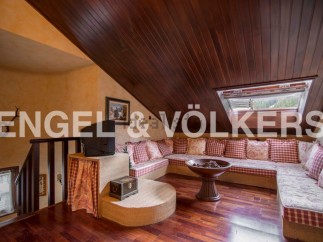 Cozy attic room with L-shaped sofa and wood-burning stove.