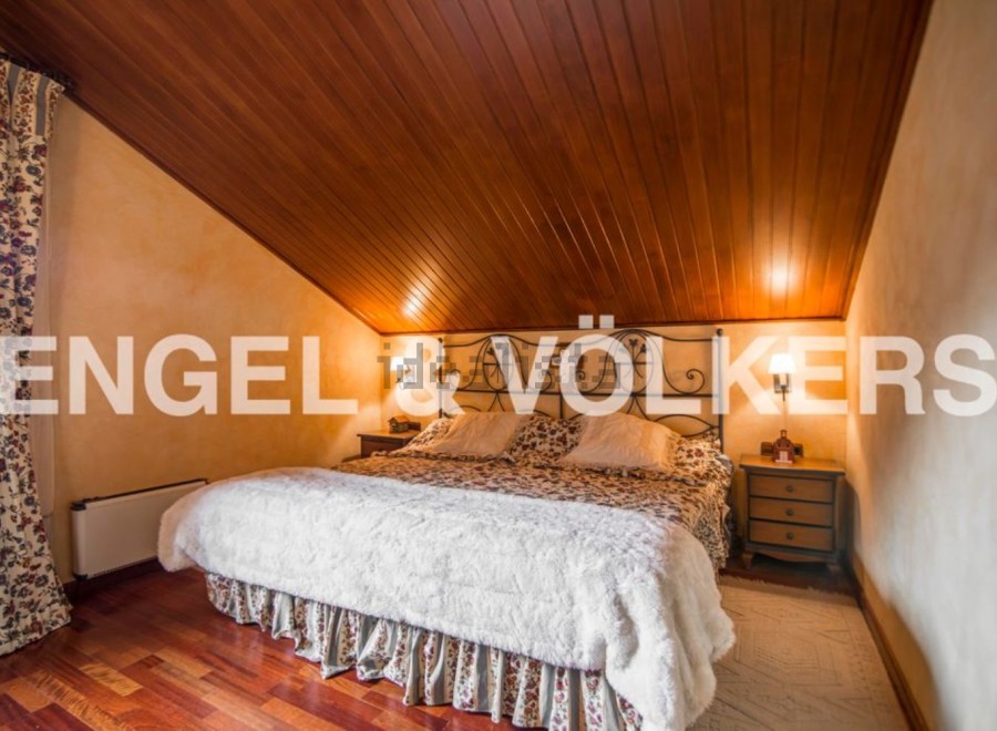 Cosy attic bedroom with wooden ceiling and hardwood floors.