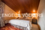 Cosy attic bedroom with wooden ceiling and hardwood floors.