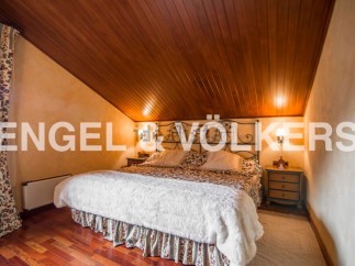 Cosy attic bedroom with wooden ceiling and hardwood floors.