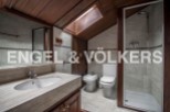 Charming attic bathroom with wooden beams, skylight, and modern fixtures.