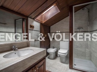 Charming attic bathroom with wooden beams, skylight, and modern fixtures.
