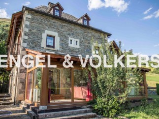 This stunning stone house boasts a spacious sunroom, perfect for enjoying the mountain views.