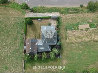This charming property boasts a spacious house with a unique architectural design, surrounded by lush greenery and a well-maintained garden.