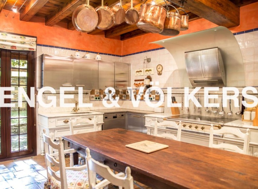 Rustic-chic kitchen with exposed wooden beams, copper cookware, and a large farmhouse table.
