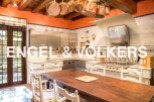 Rustic-chic kitchen with exposed wooden beams, copper cookware, and a large farmhouse table.