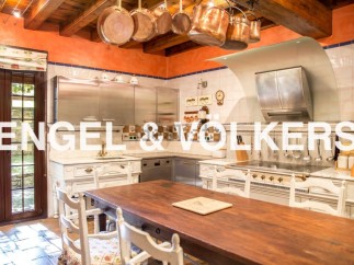 Rustic-chic kitchen with exposed wooden beams, copper cookware, and a large farmhouse table.