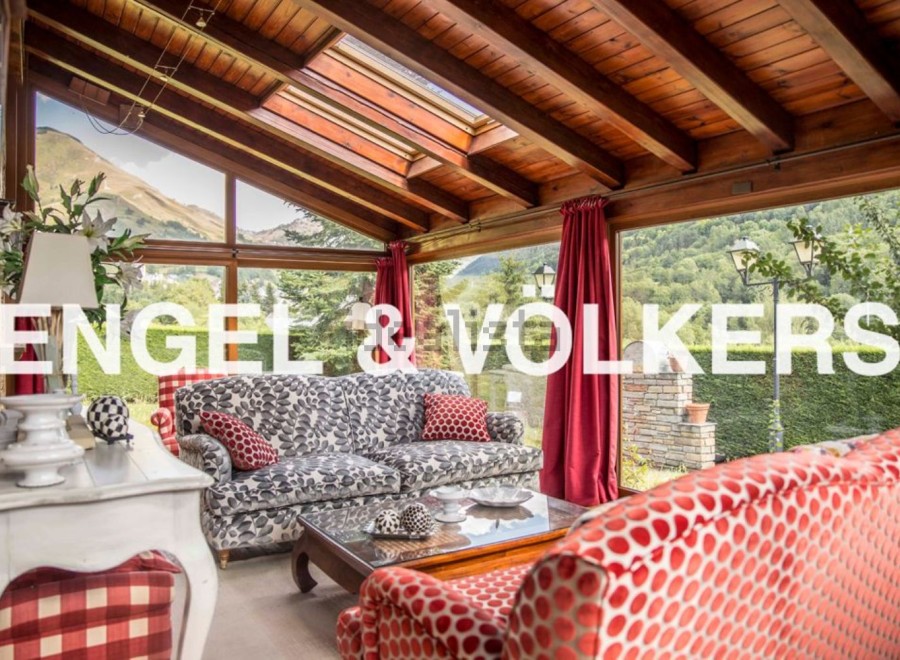 Sun-drenched conservatory with stunning mountain views, featuring comfortable sofas and a wooden beamed ceiling.